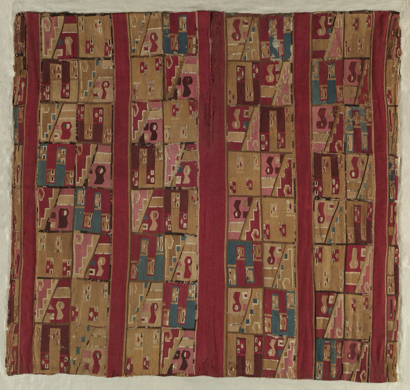 Wari tunic woven with a grid of repeated geometric figures in red, ochre, pink, and blue